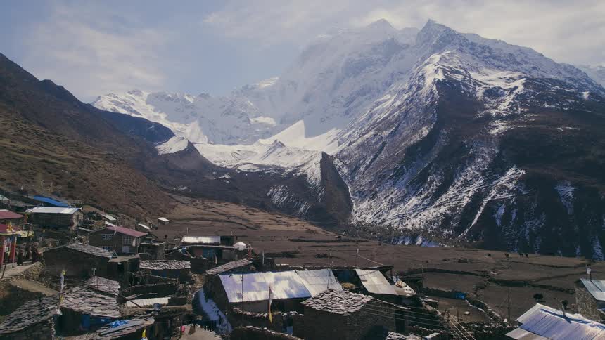 A small town close to a mountain covered in snow