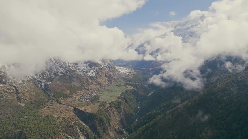 Clouds cover a mountain range with a river running through the valley
