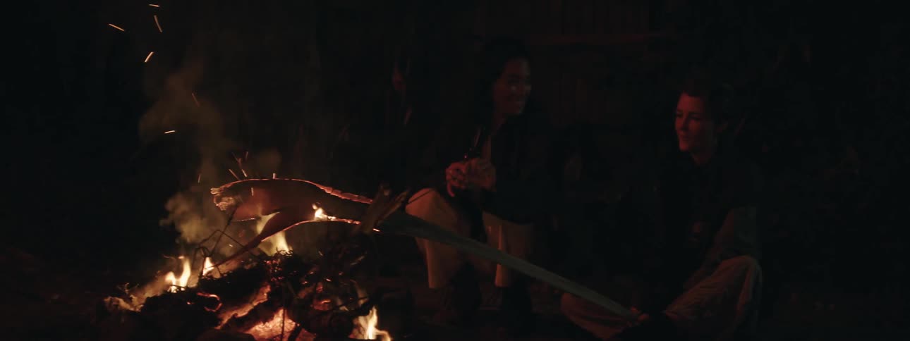 Women sit by bonfire oudoors at night