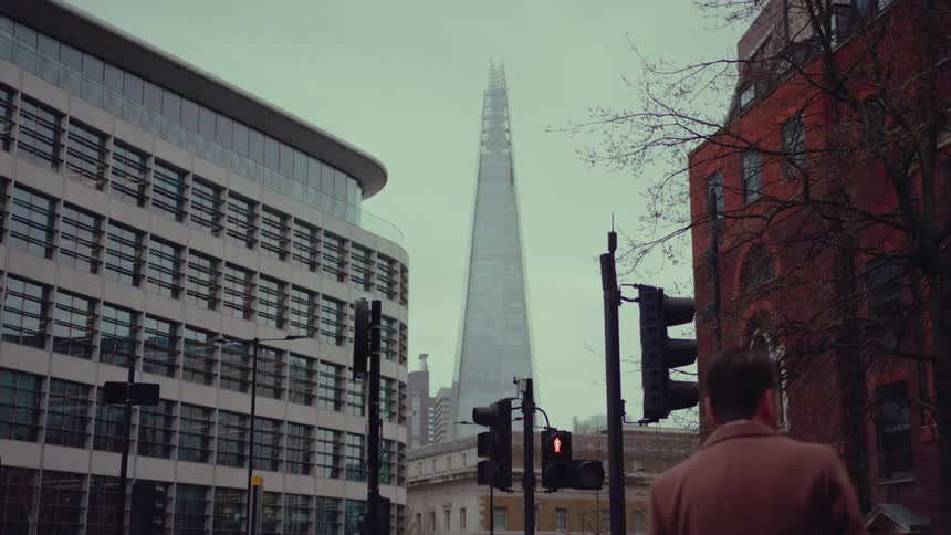 A man looks around while walking in the city. The shard in the background