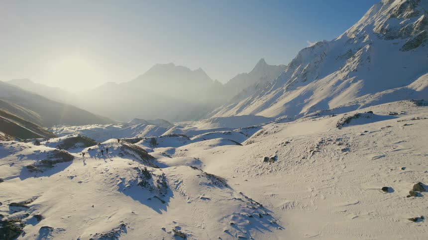 Three people walking on snowy terrain under cloudy sky