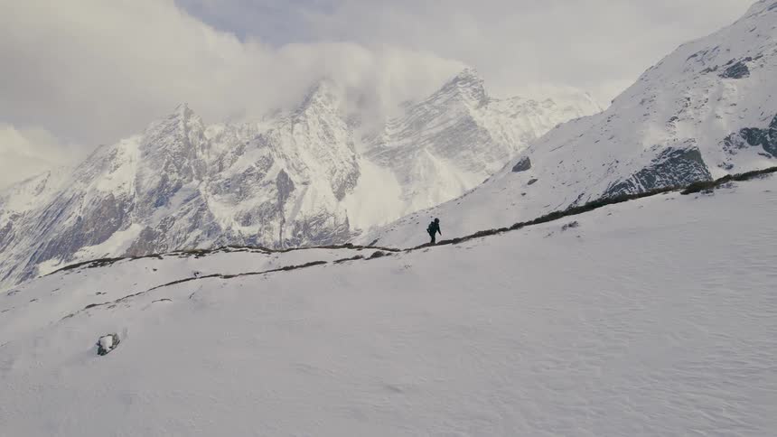 Hiker walks up slight slope on snow covered mountain
