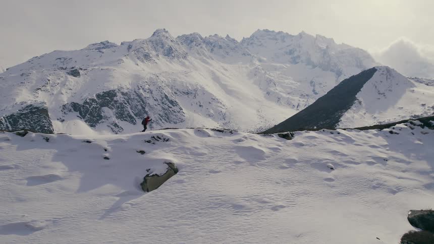 A person hiking on top of the mountain covered in snow