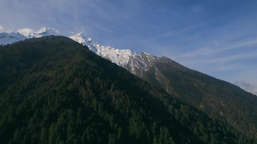 Valley separates forest covered mountain from snow capped mountains