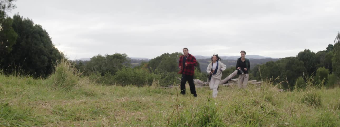 Two women and a man run on country road in the forested area