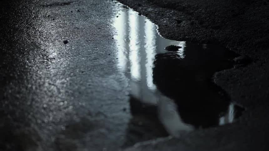 A person is walking in the reflection of a puddle