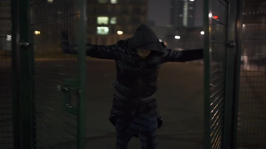 A man walks and opens a gate with two arms