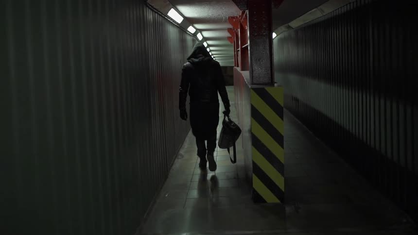 A man is walking down a tunnel with a bag