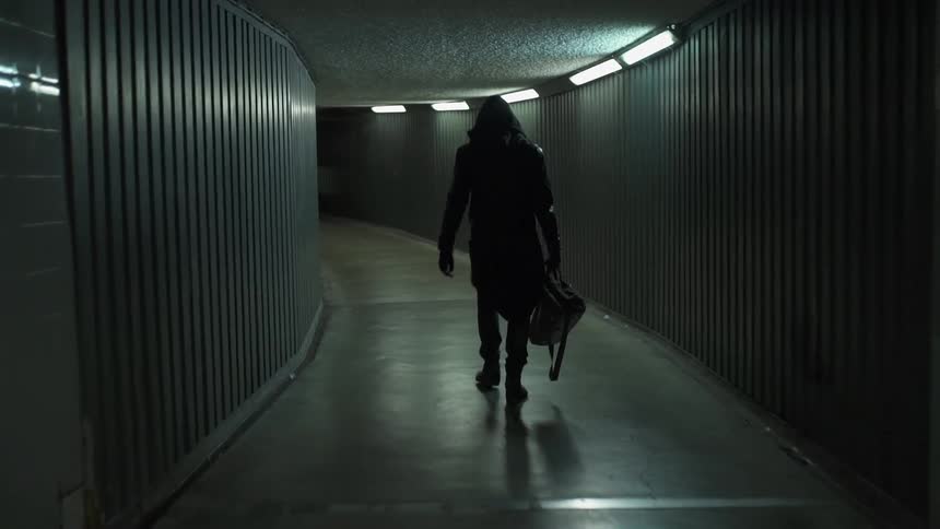 A man is walking down a hall carrying a bag