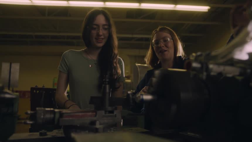 A teacher is showing a student a machine