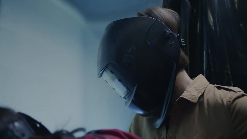 Two people wearing face shields are welding