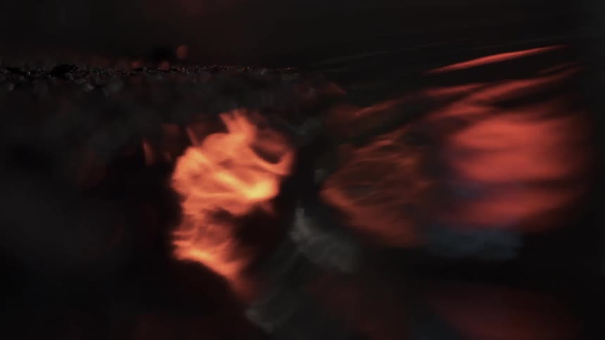 Red and white lights are reflected in a puddle