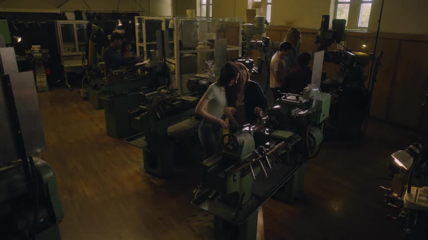Teacher helps a student with a lathe in the workshop