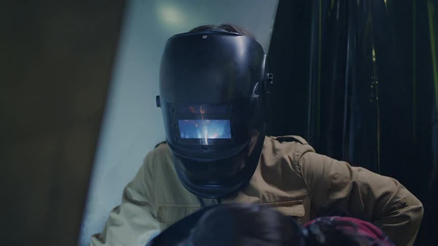 Two workers with protective masks soldering