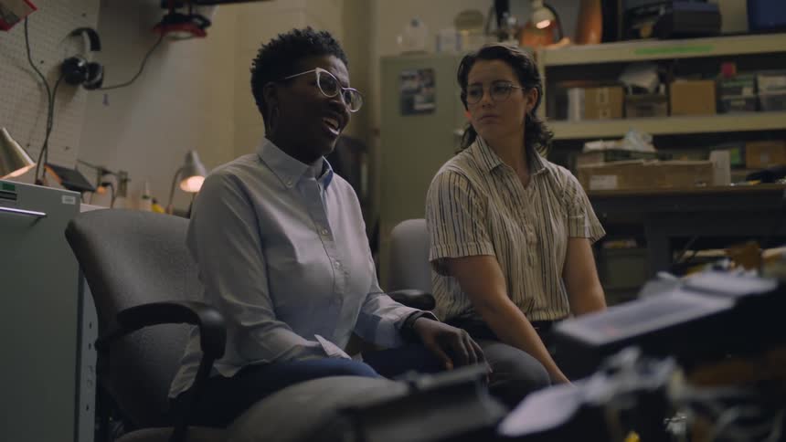 Woman sitting on a small office talks next to a friend