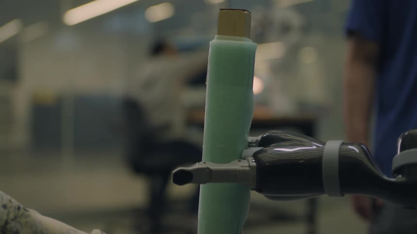 Robotic hand holds a foam stick on a lab