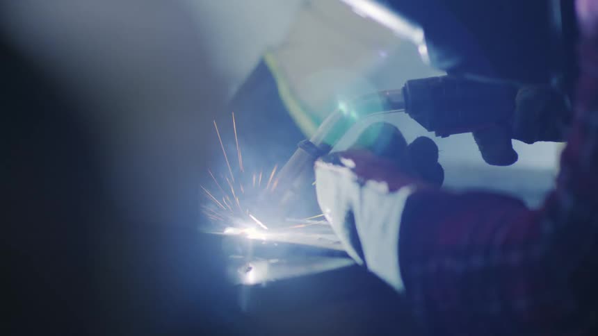 Person in protective gear welding over a table indoors