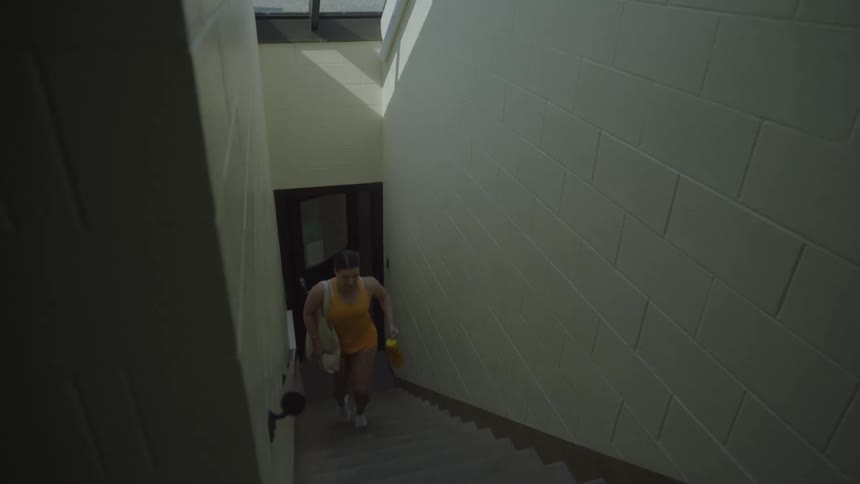 White woman in yellow clothes carrying a handbag rushing upstairs