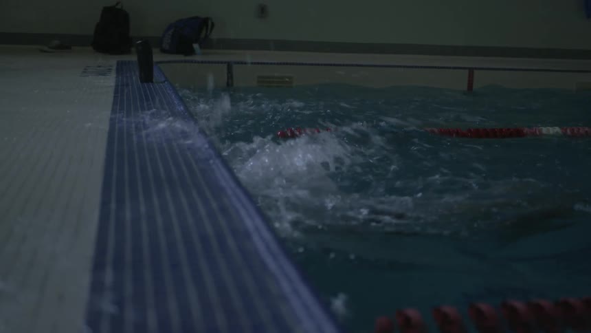 Two people in a swimming pool reach the wall and the turn around under water