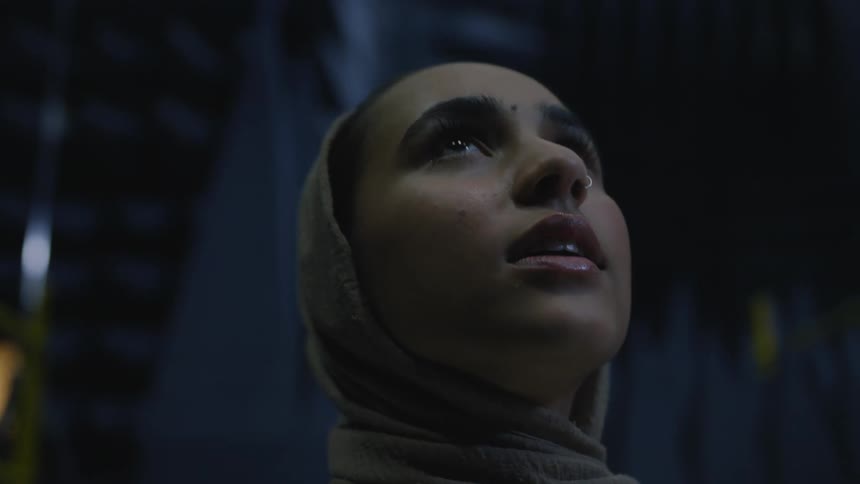 A woman in a headscarf talks while inspecting the room she is in