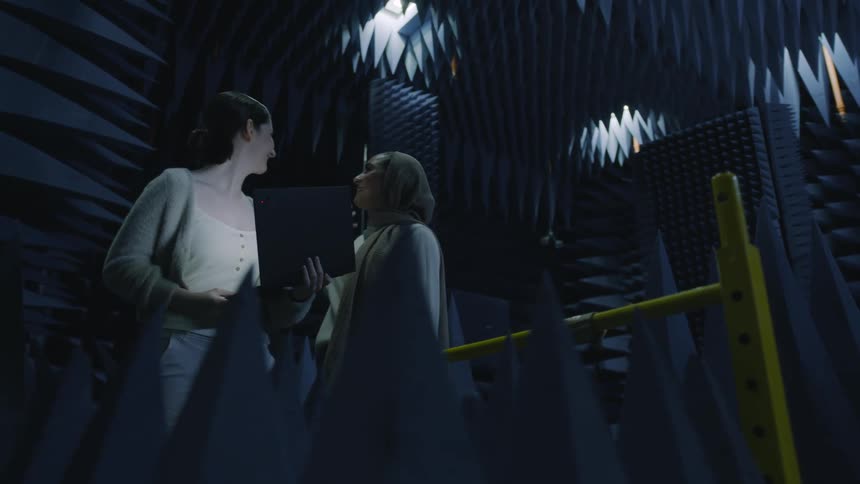 Two young women stand on a recording studio padded with acoustic foam