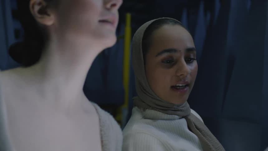 Two women stand next to each other while discussing the layout of a room