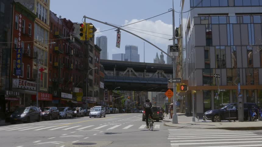 Black man cycling through a crossing in a metropolitan area with other people and traffic around in day time