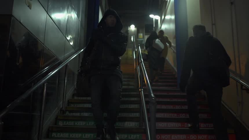 Man wearing hooded jacket going down stairs in a city
