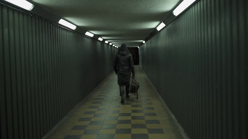 A man is walking down a long hall