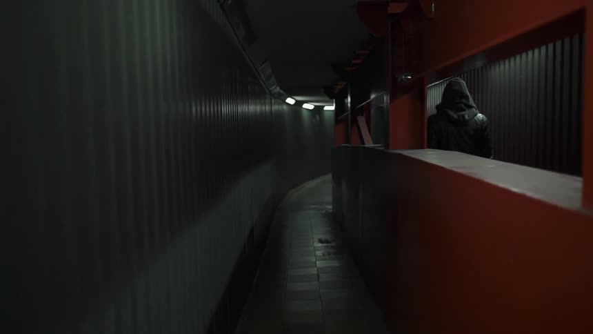 A man carries a bag through a tunnel