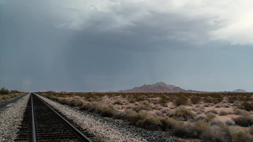 Lightning is shooting from the clouds by the train tracks