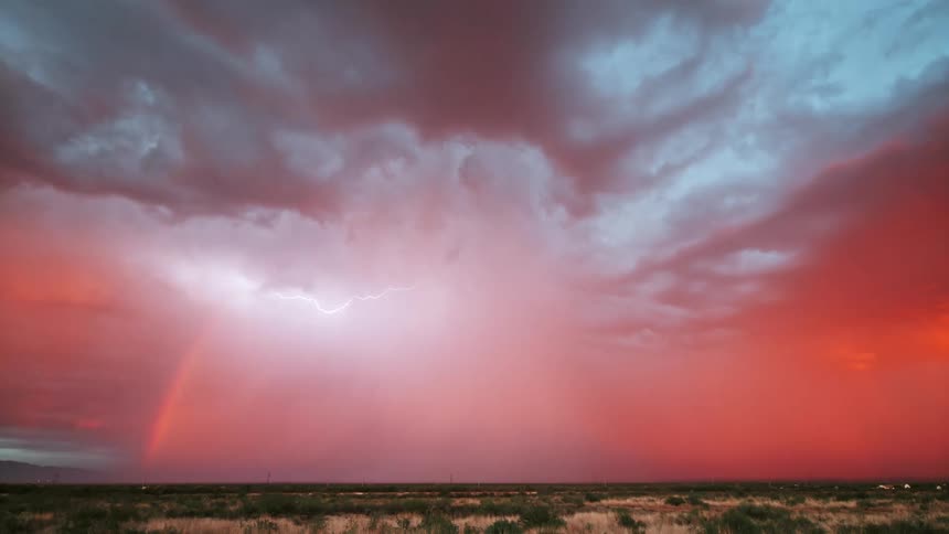 A lightning storm lighting up a bright pink sky over a wide open landscape