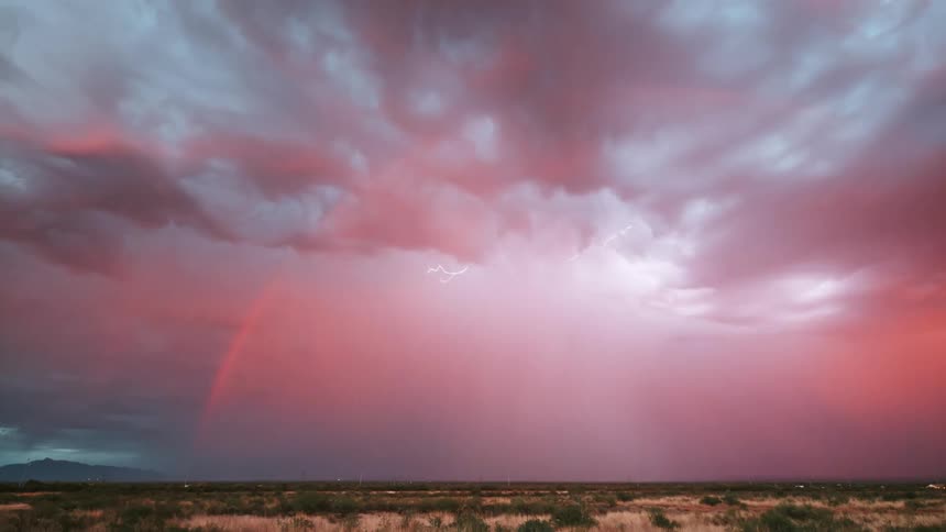 A lightning storm flashing in the pink sky over a wide open landscape