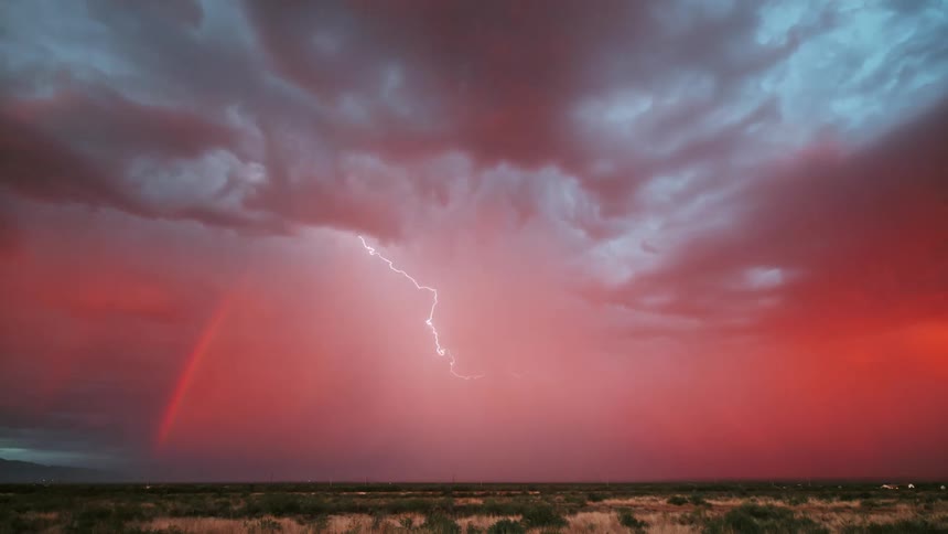 A lightning storm streaking across the pink cloudy sky over flat prairies
