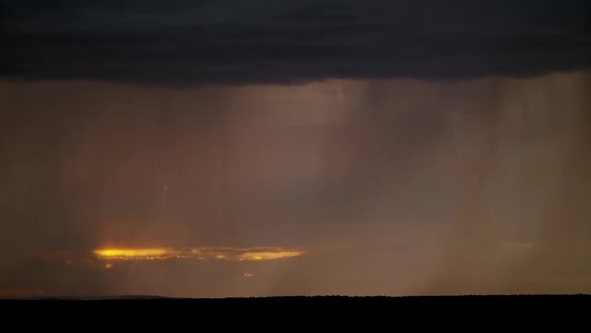 Lightning storm clouds allow amber sunlight to shine through
