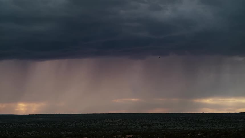 In the sky a dark cloud hovers just above a slightly less dark cloud forming an imposing thunderstorm frequent lightning strikes illuminate the scene