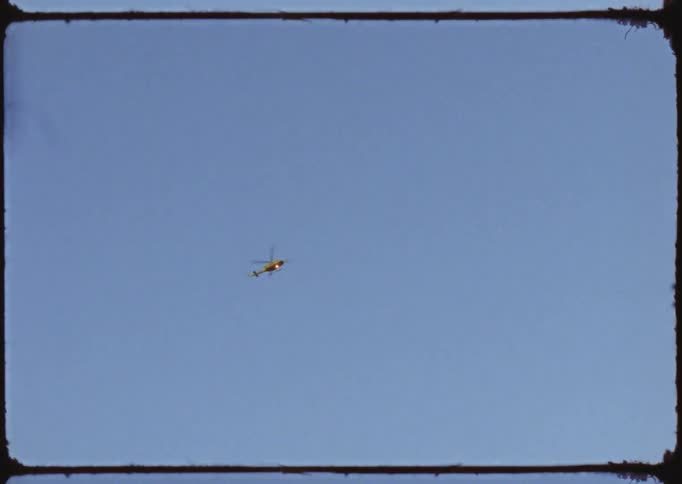 A helicopter flying over the sky on a clear blue cloudless day