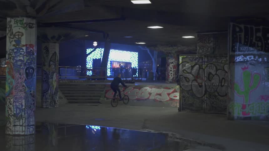 A bicyclist rides in a heavily graffitied skate park