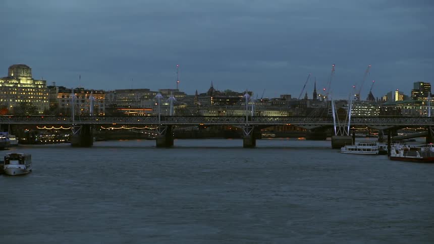 Boats float with a bridge and city buildings in the background