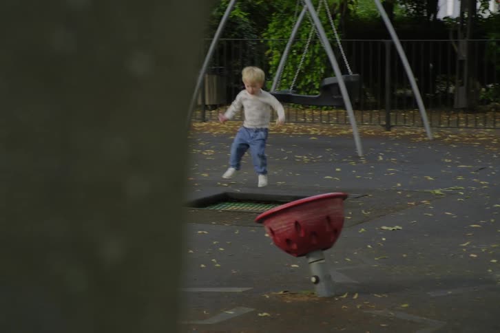 Blonde boy jumping on a trampoline in a park