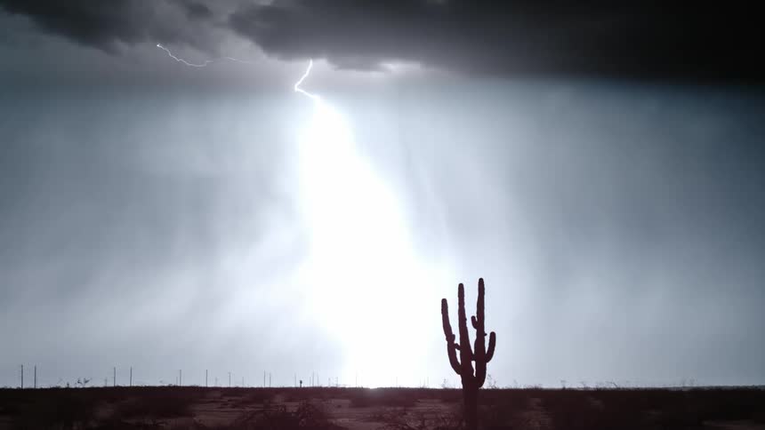 A heavy lightning storm cutting through the night sky above a desert