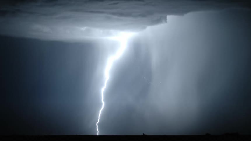 Bolts of lightning illuminate the night sky over a grassland