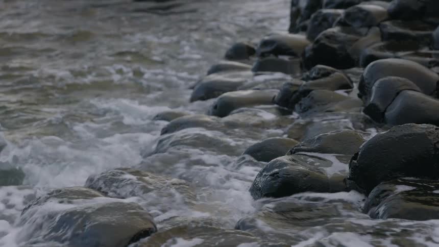 Small waves gently crashing onto round rocks