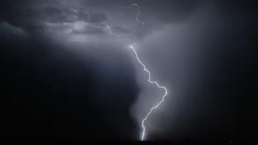 Lightning cracks across the darkness of the night sky and illuminates the clouds with flashes of light