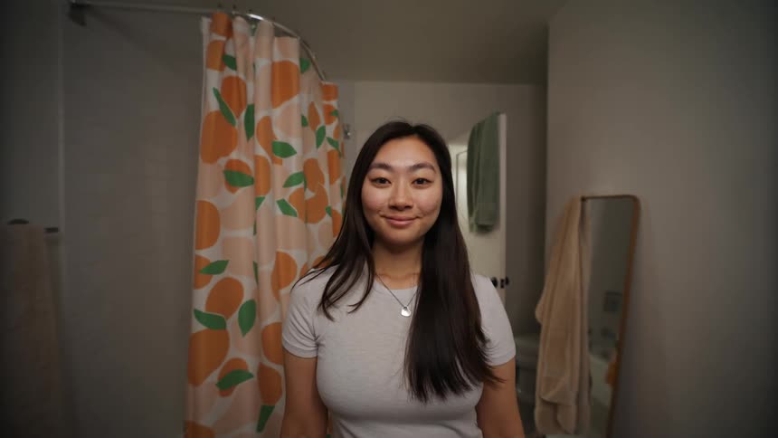 Asian woman adjusting her hair on a bathroom indoors