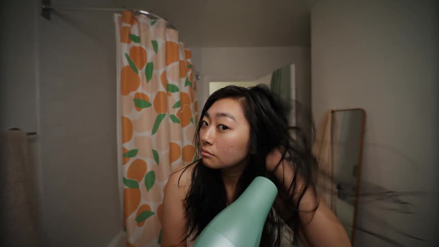 Young woman uses a hair drier in the bathroom at home