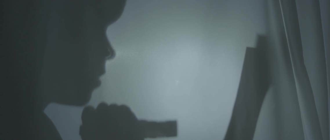 A child reads behind a curtain in the dark
