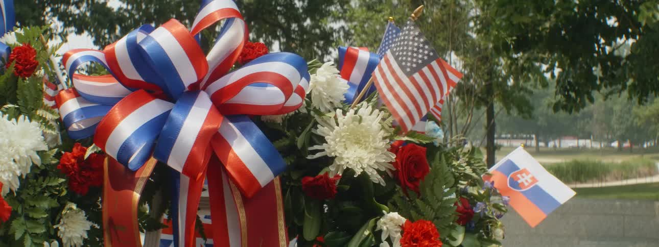 A close up of a patriotic and memorial wreath with flags in the middle of the day