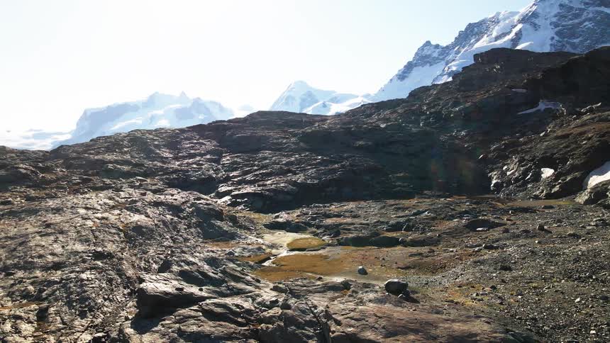 A valley in a mountain range with snow capped mountains in the background