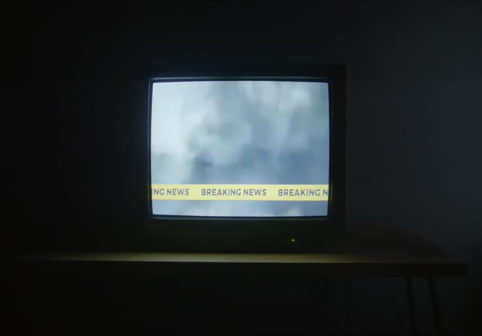 Television broadcasts breaking news in dark room